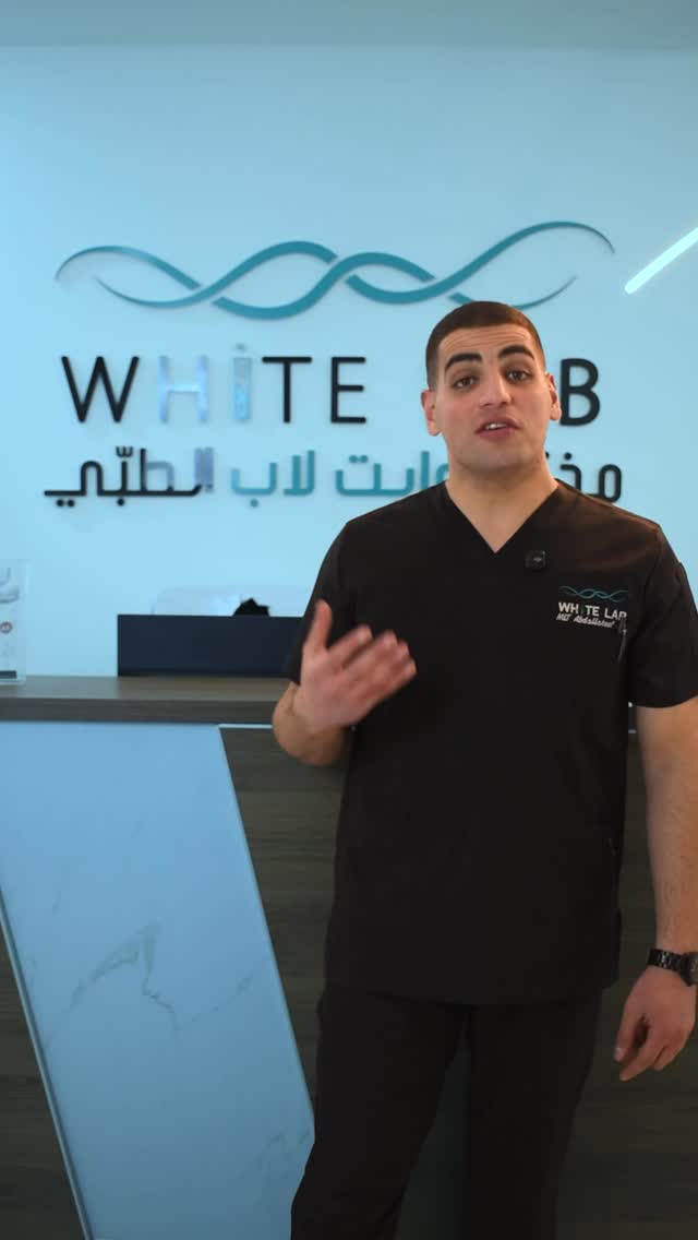 أحد أفراد فريق وايت لاب أمام استقبال المختبر وشعار وايت لاب خلفه