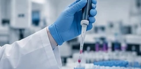 يد فني بقفاز طبي تستخدم ماصّة داخل المختبر
